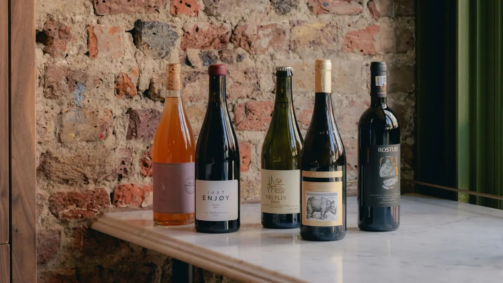 Five bottles on a marble ledge against the bare brick wall.