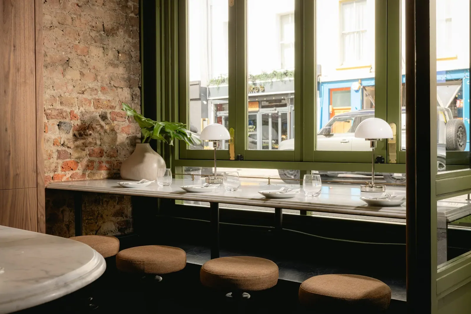 The window ledge onto Blenheim Crescent - marble, cork stools and dome lamps against bare brick.